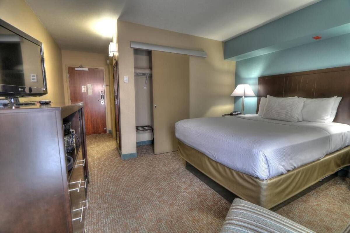 Habitación de hotel con cama, escritorio con televisor, armario y baño.
