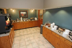 Cozinha com armários de madeira, máquina de café e lixeira.
