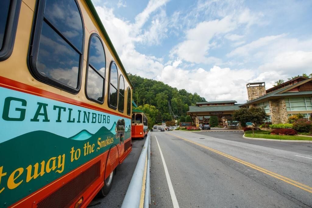 A bus with 'GATLINBURG' and 'Gateway to the Smokies' written on it, parked on a road with a building in the background.