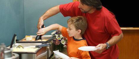 Un hombre y un niño en una cocina, preparando comida.