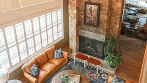 A cozy living room with a stone fireplace, leather sofas, and a chandelier.