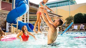 A swimming pool area with a water slide and a building in the background.