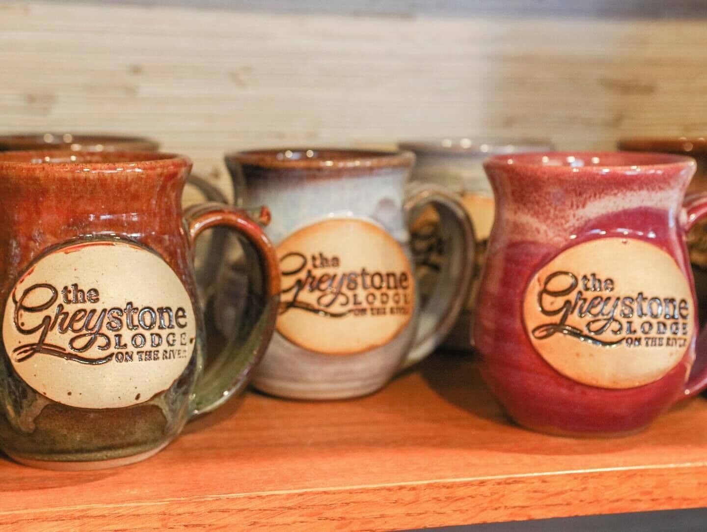 A row of ceramic mugs with the text "the Greystone Lodge" on them.
