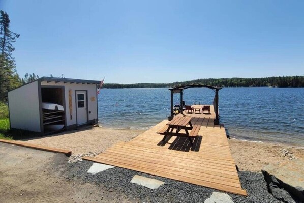 Un muelle con una mesa de picnic y una cabaña pequeña junto al lago.