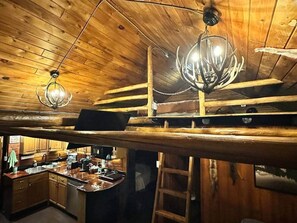 Un interior rústico de madera con cocina, una litera y un candelabro.