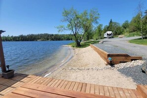 Una terrazza sul lago con una passerella in legno, un piccolo pontile e un’area con ghiaia.