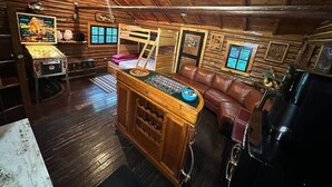 En mysig stuga med en träinredd bar, lädersitsar och inramade tavlor på väggarna.