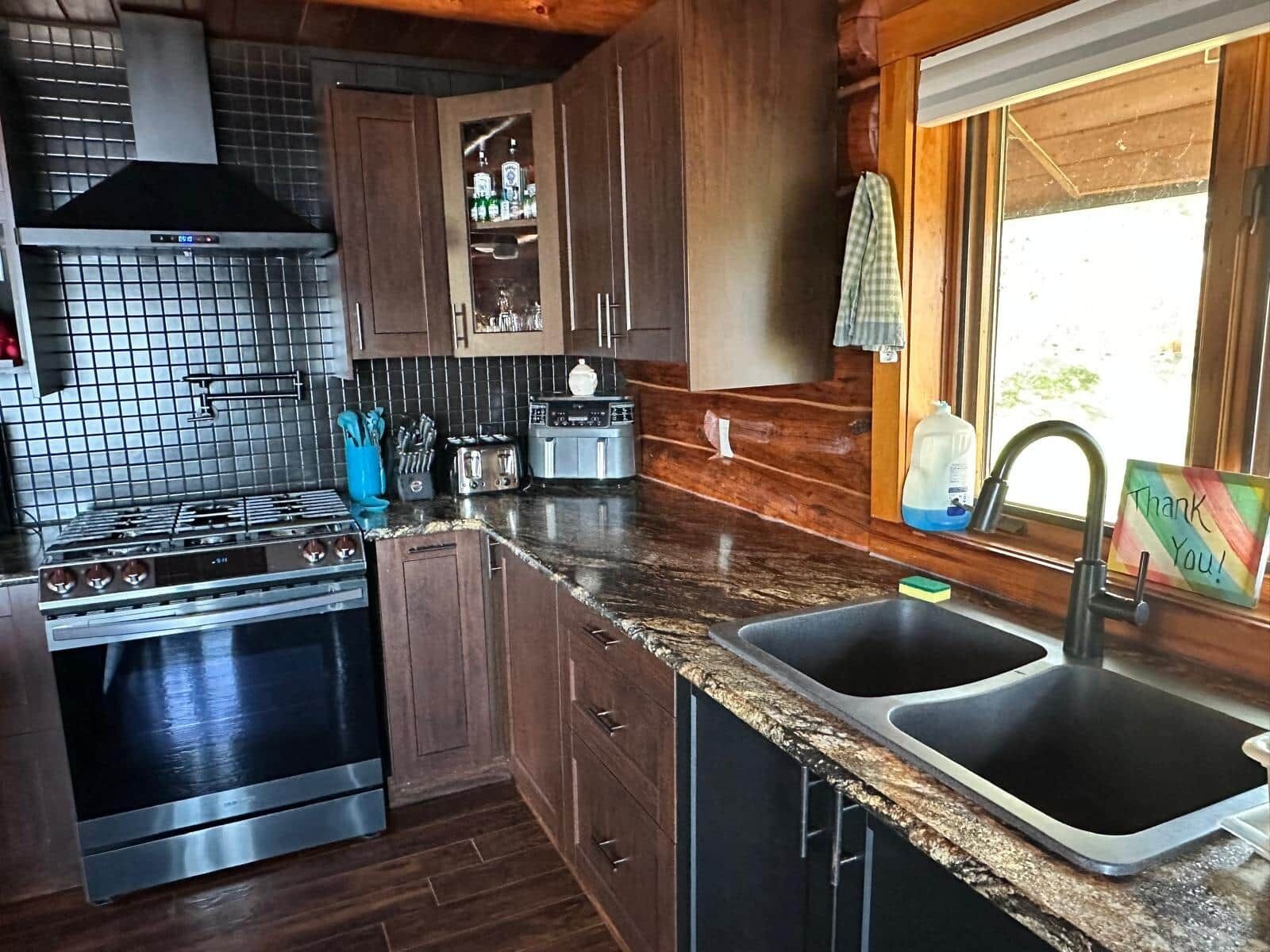 A kitchen with a stainless steel stove, a built-in oven, a microwave, a toaster, and a sink.