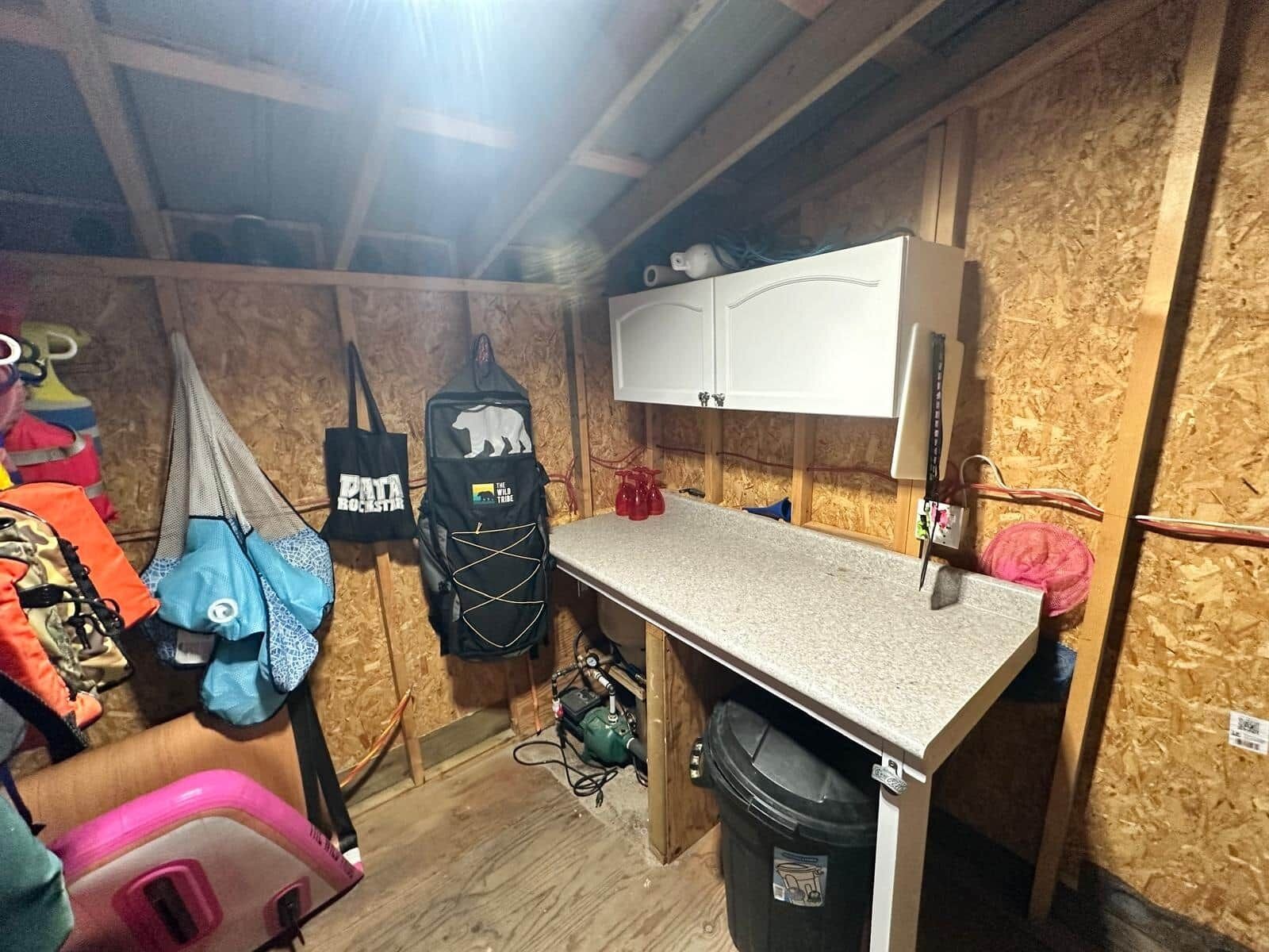 A compact kitchen with a countertop, cabinets, and a trash bin.