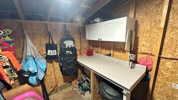 A compact kitchen with a countertop, cabinets, and a trash bin.
