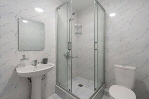Ein Badezimmer mit einer Duschkabine, einem weißen Waschbecken und einer Toilette.