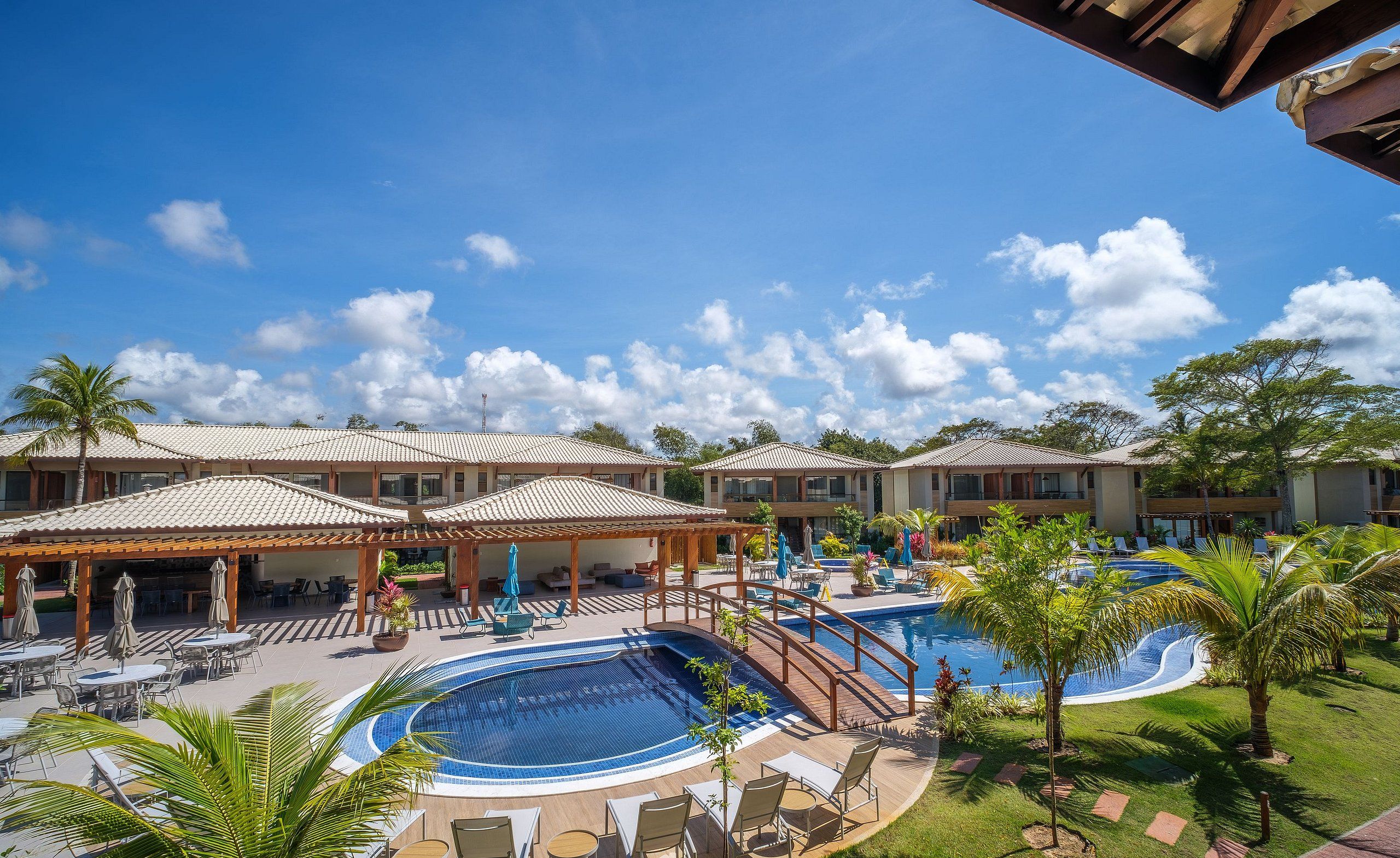 A resort with a swimming pool, outdoor seating, and covered areas.