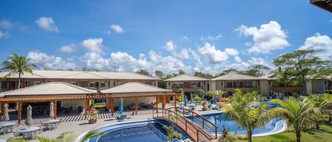 A resort with a swimming pool, outdoor seating, and covered areas.
