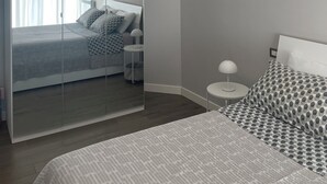 A bedroom with a large mirror, a chandelier, a bed with patterned bedding, and a bedside table with a lamp. - (Vatican area) apartment X 4 WI-FI balcony, air conditioning  (Roma)