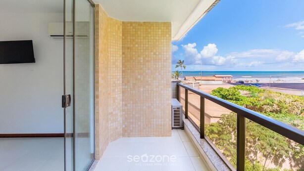 Ein Balkon mit Blick auf den Strand, eine Glastür und eine geflieste Wand.