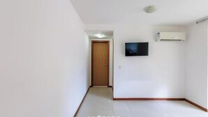 Ein Flur mit einer Holztür, einem Wand-Fernseher und einer Klimaanlage an der Wand.