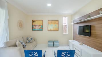 A living room with a sofa, TV, and artwork on the wall.