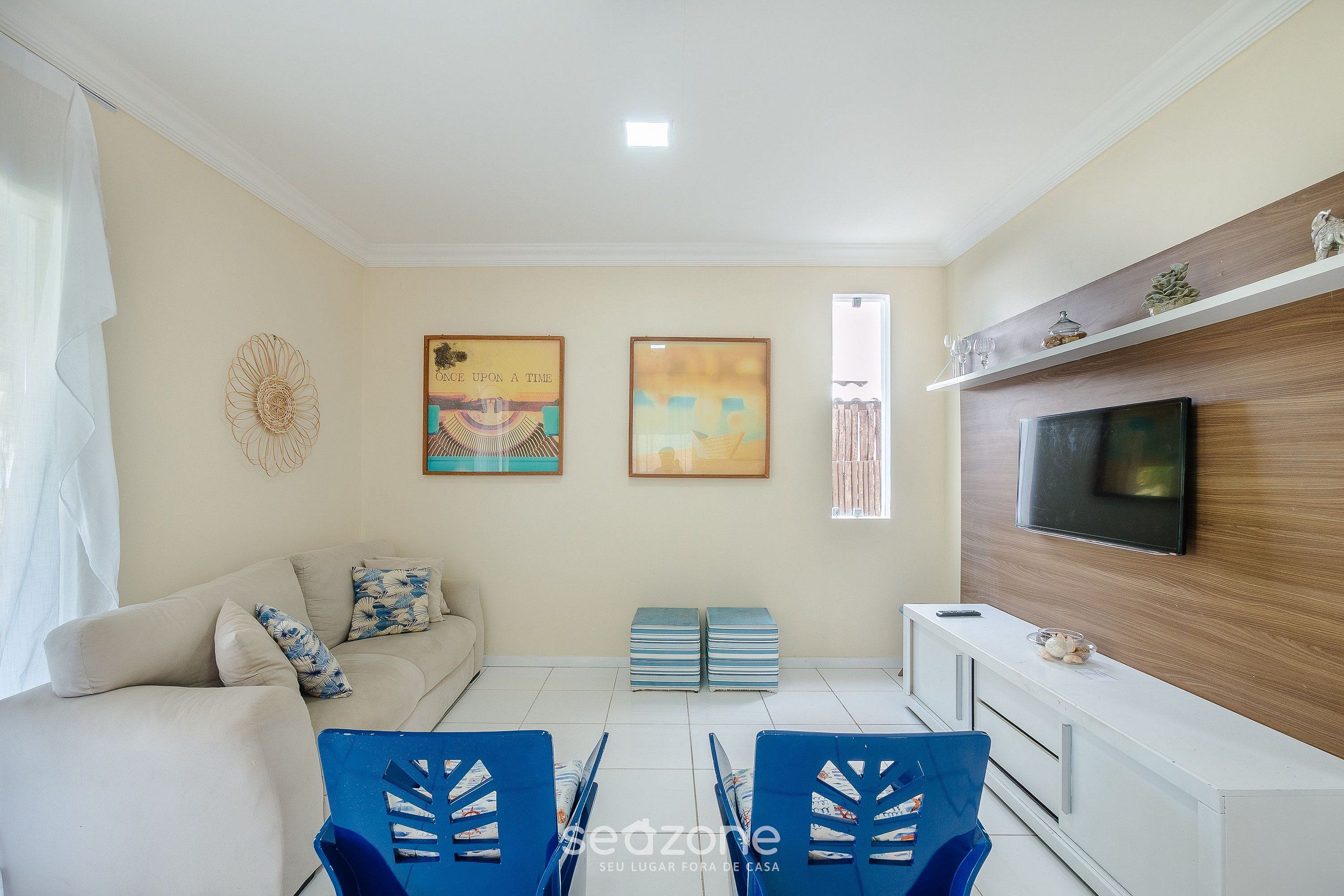 Una sala de estar con sofá, televisión y una obra de arte en la pared.