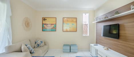 Una sala de estar con sofá, televisión y una obra de arte en la pared.