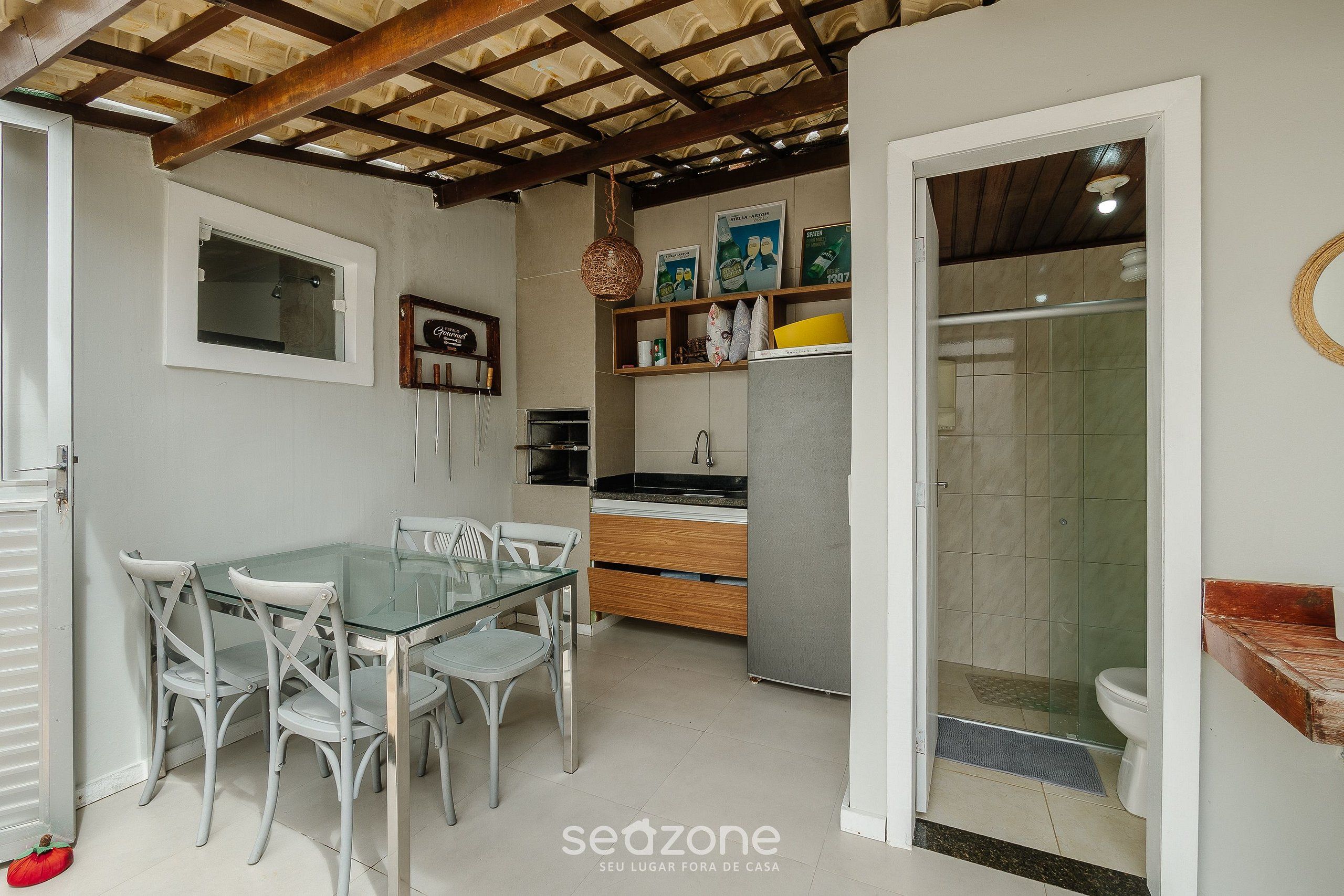 A compact kitchen with a glass dining table and chairs, a built-in oven, and a small refrigerator.