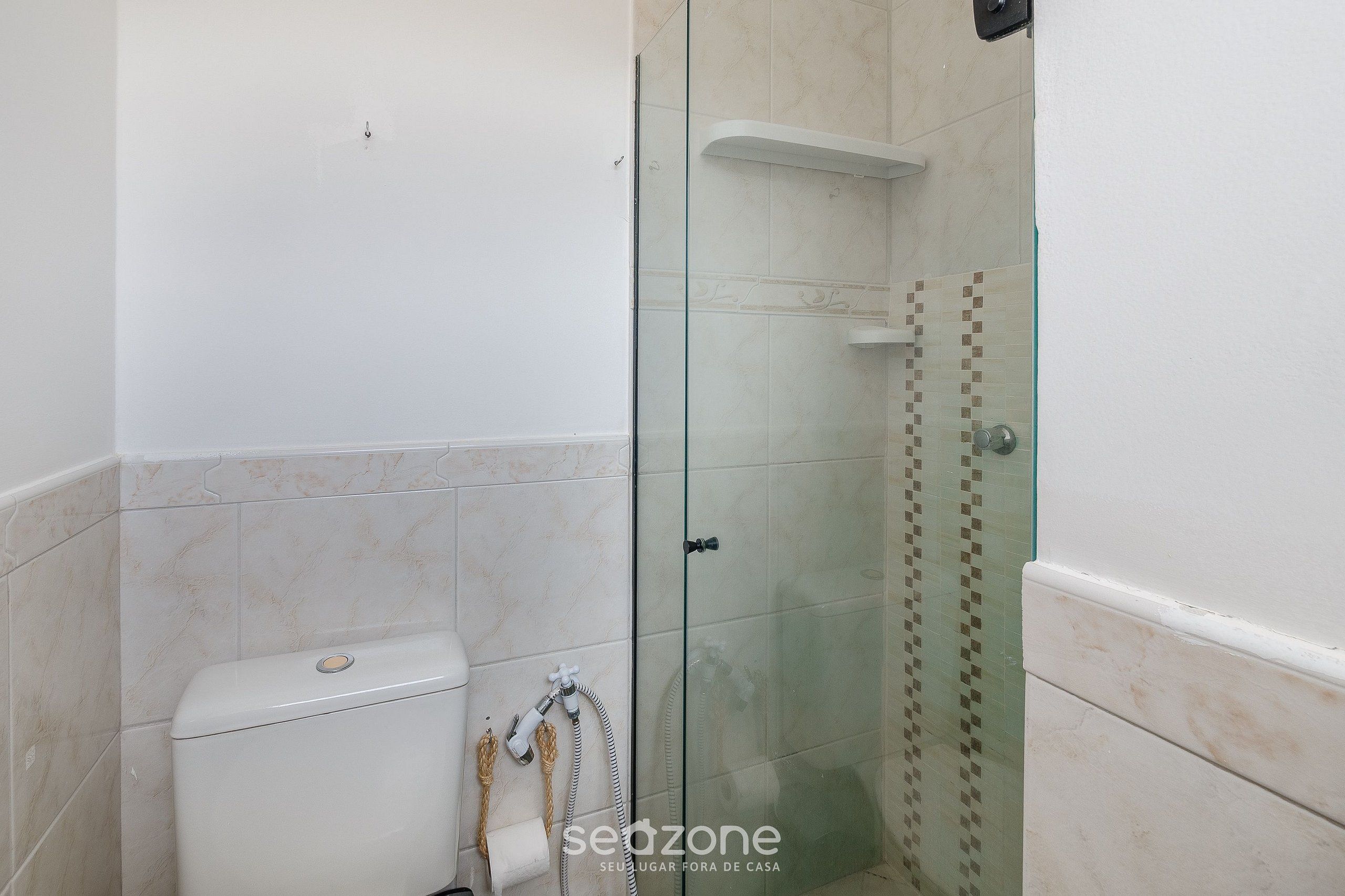 Un baño con ducha de vidrio, inodoro y perchero para toallas.