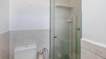A bathroom with a glass-enclosed shower, a toilet, and a towel rack.