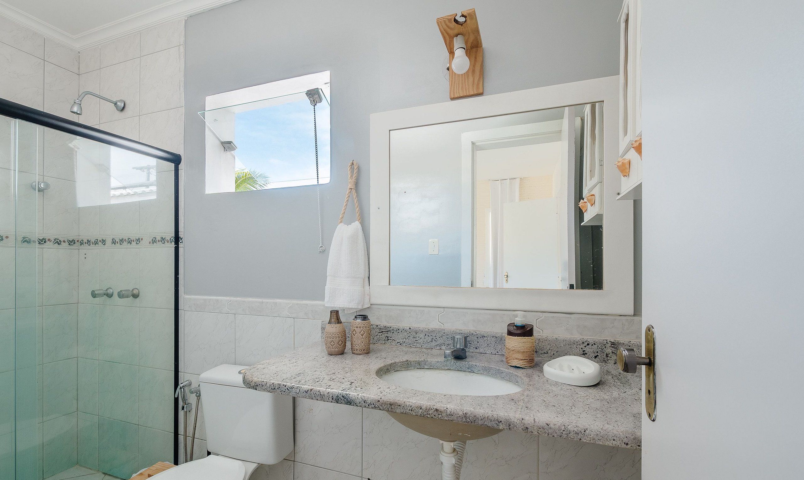Un baño con cabina de ducha de vidrio, un lavabo con encimera de granito y un espejo sobre el lavabo.
