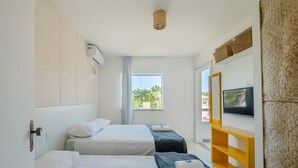 Habitación de hotel con dos camas, un televisor en la pared y ventana con vistas a zonas verdes.