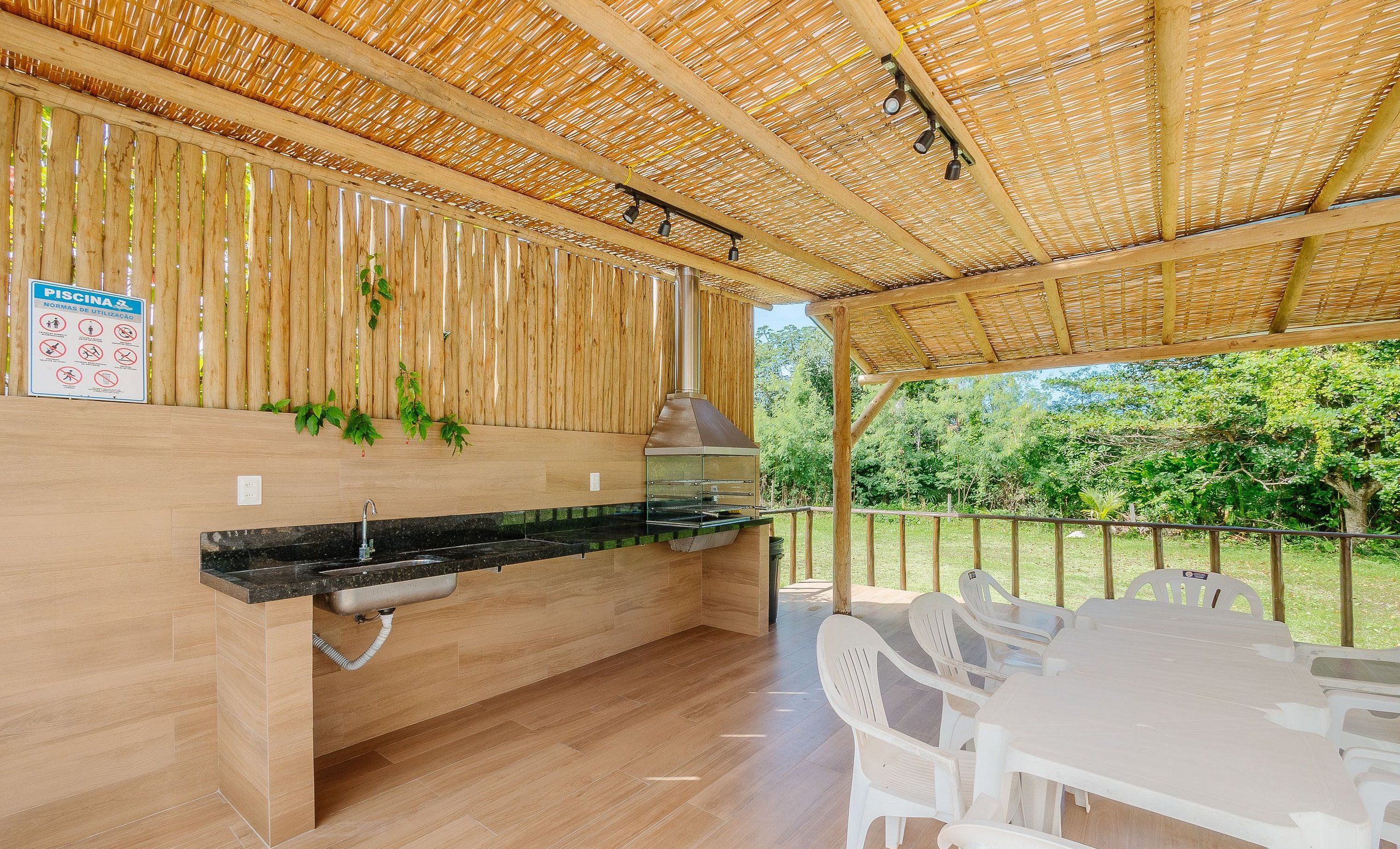 An outdoor kitchen area with a grill, a sink, and a table with chairs.