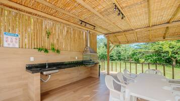 An outdoor kitchen area with a grill, a sink, and a table with chairs.