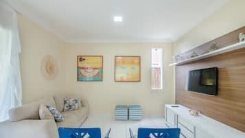 Una sala de estar con sofá, televisión y una obra de arte en la pared.