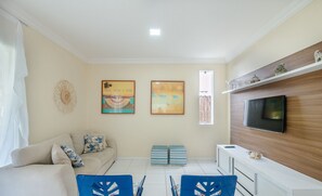 A living room with a sofa, TV, and artwork on the wall. - Spacious House w/ Pool in Guarajuba Cag0003 (Camaçari)