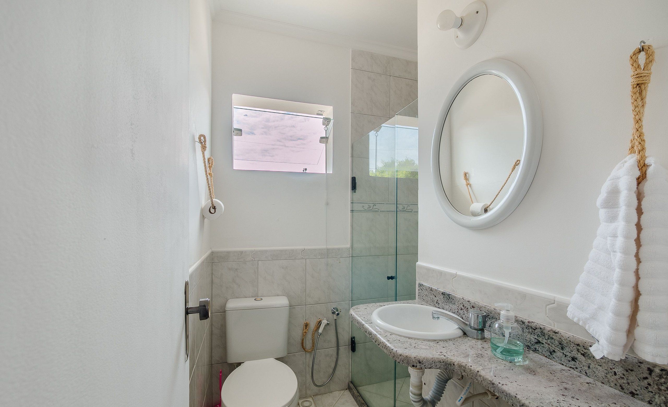 Un baño con inodoro, lavamanos, espejo y ducha.