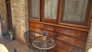 A stone-walled outdoor seating area with a round table and four chairs.