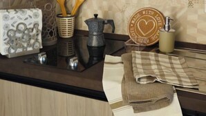 A kitchen counter with a coffee maker, wooden utensils, a decorative plate, and a cloth.
