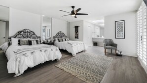 A modern bedroom with two beds, a ceiling fan, and a large window. - GATED, Spacious 2-bedroom condo in Indian Wells close to restaurants and more. (Indian Wells)