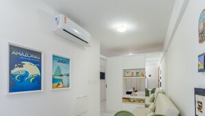 Una habitación moderna y bien iluminada, con techo blanco, unidad de aire acondicionado y un comedor con mesa y sillas.