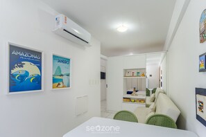 A modern, well-lit room with a white ceiling, air conditioning unit, and a dining area with a table and chairs. - Near the sea and the Best of Recife! Cav0411 (Recife)
