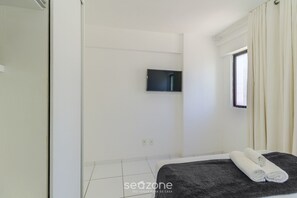 A room with a bed, a television mounted on the wall, and a window with curtains. - Near the sea and the Best of Recife! Cav0411 (Recife)