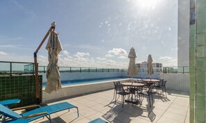 A rooftop pool area with blue lounge chairs, a pool, and umbrellas. - Near the sea and the Best of Recife! Cav0411 (Recife)