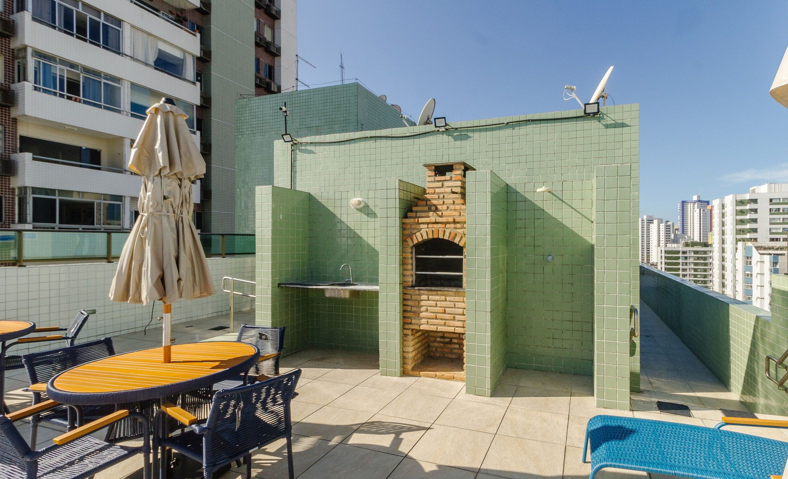 Una terrazza sul tetto con un camino in mattoni, posti a sedere all'aperto e vista sulla città.