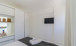 A bedroom with a bed, a TV mounted on the wall, and a wardrobe. - Near the sea and the Best of Recife! Cav0411 (Recife)