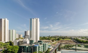 Un edificio de gran altura con varios pisos, rodeado de otros edificios y zonas verdes.