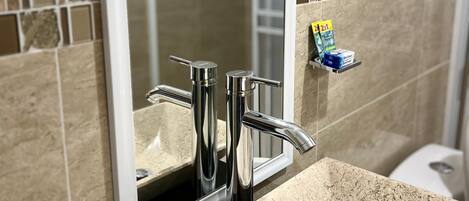 A bathroom with a rectangular sink, chrome faucets, and a mirror.