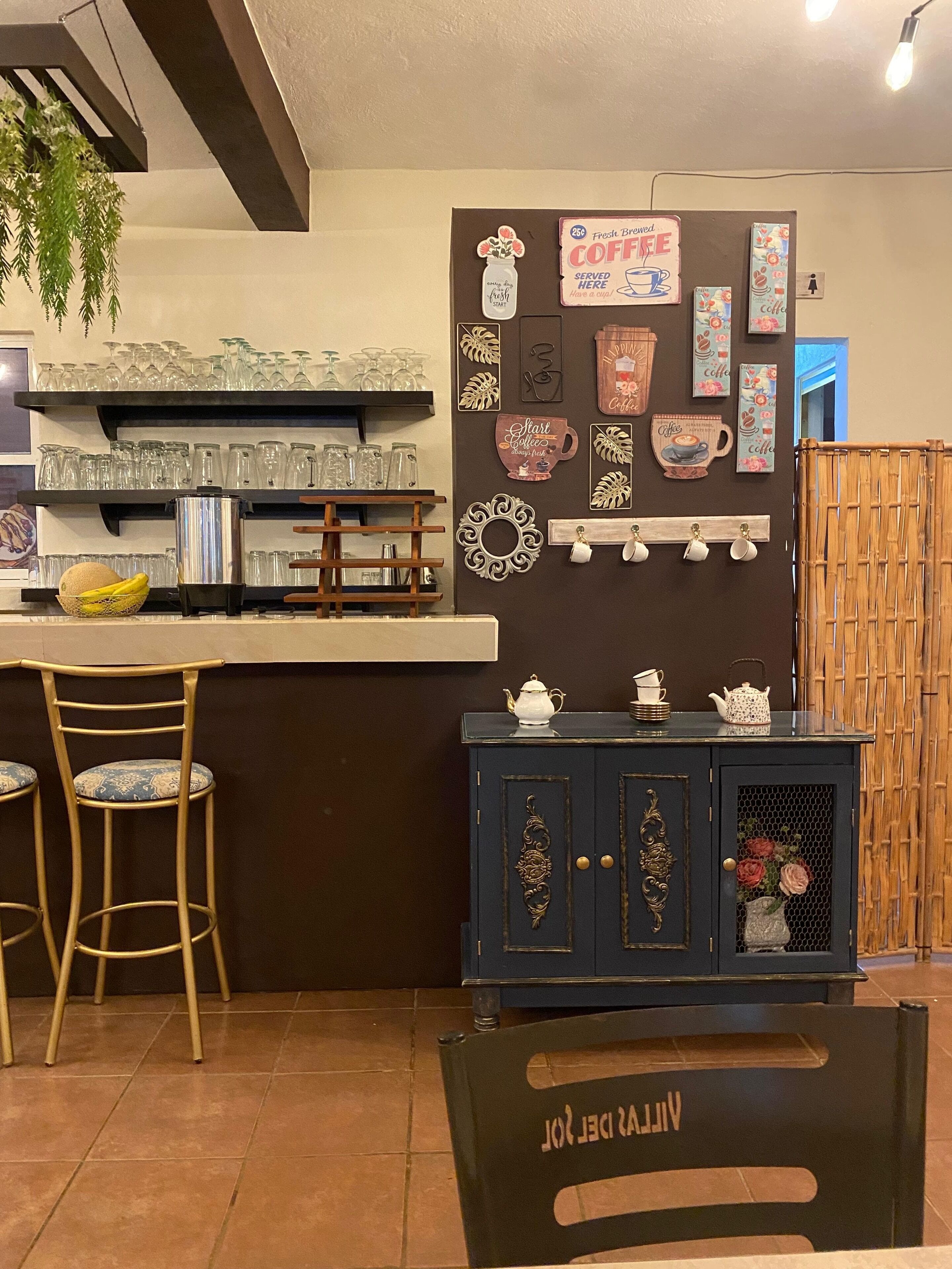 En bardisk med barstolar, en kaffestation och dekorativ väggkonst.