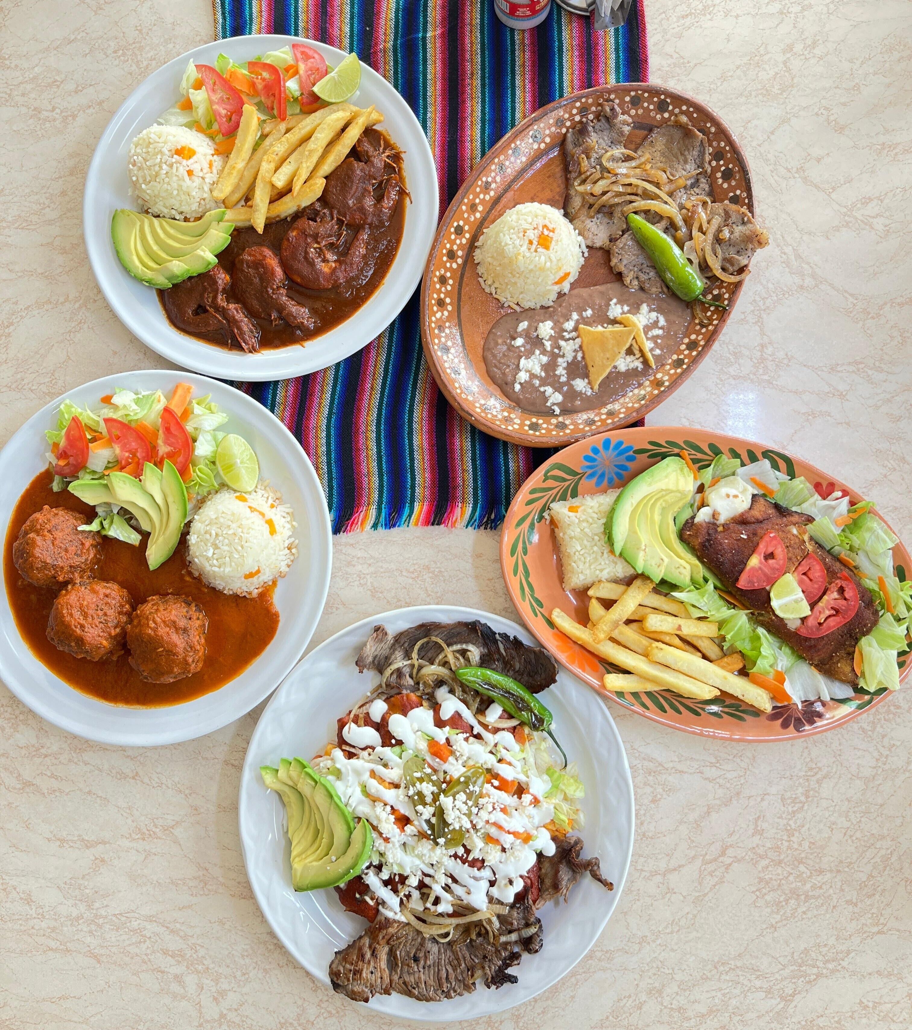 Una mesa con diversos platos, incluyendo carne, arroz y verduras.