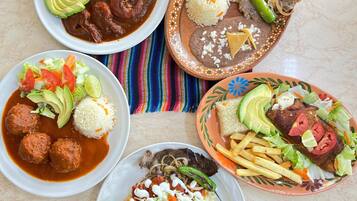 Una mesa con diversos platos, incluyendo carne, arroz y verduras.