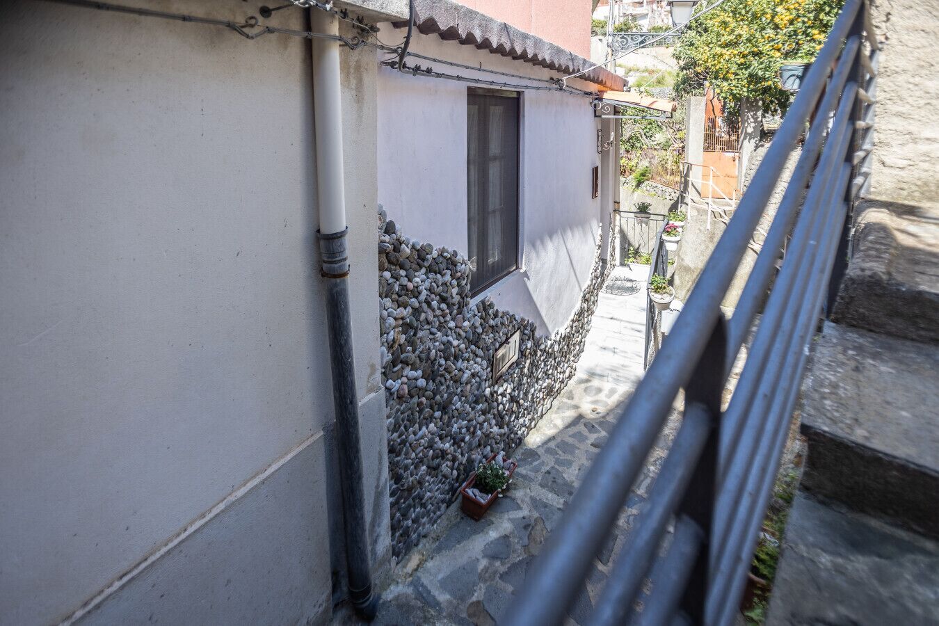 Un estrecho callejón con un edificio blanco, una ventana y una pequeña planta en maceta.