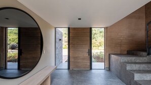 Ein modernes Interieur mit einem gewölbten Spiegel, einer Holztür und einer Treppe, die zu einem Außenbereich führt.