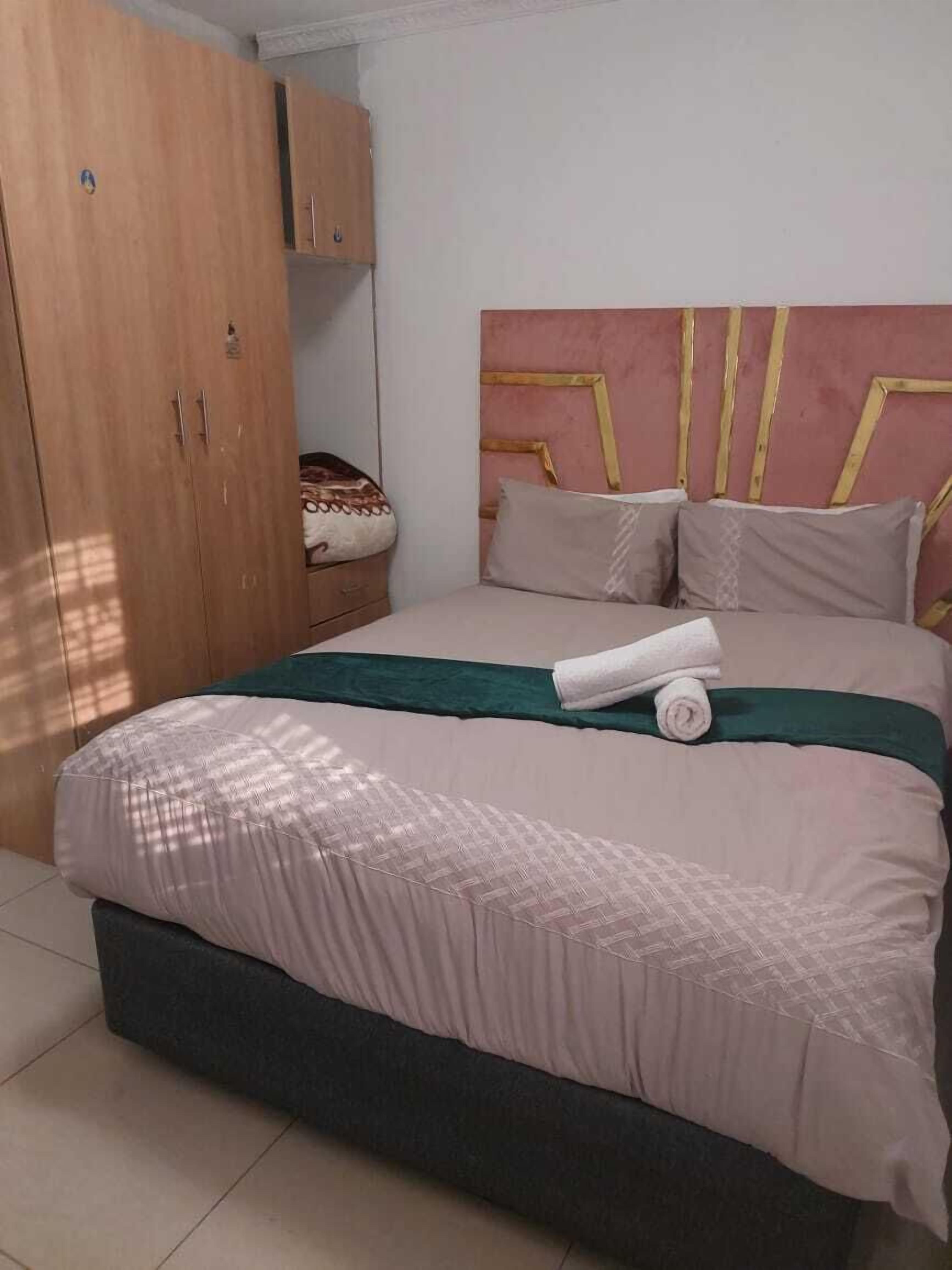 Un dormitorio con cama, armario y cabecera.